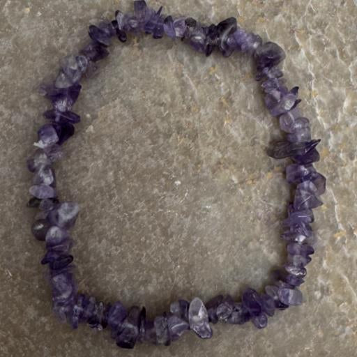 Purple crystal chip bracelet on a stone surface