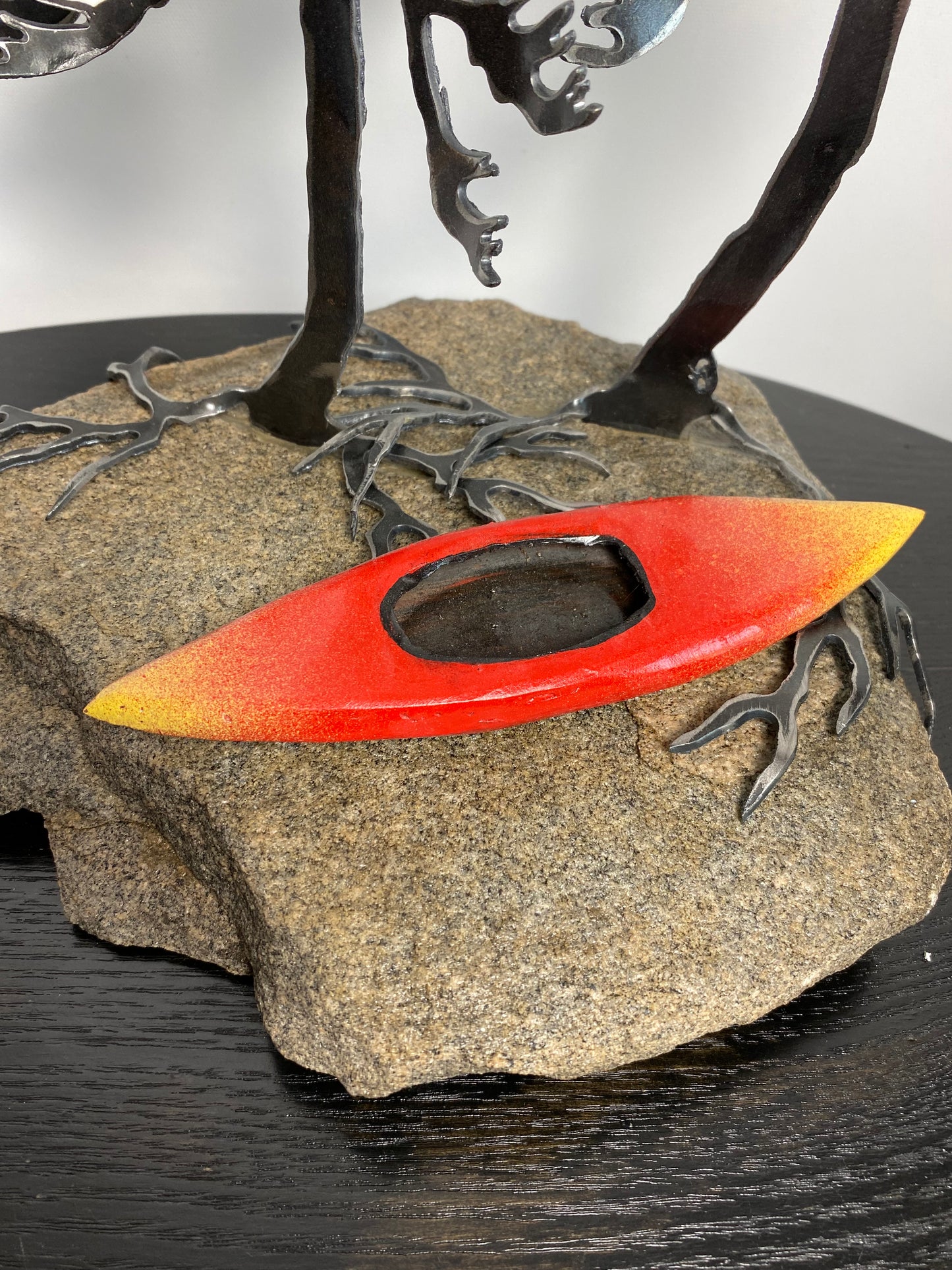 Metal windswept tree with kayak on granite