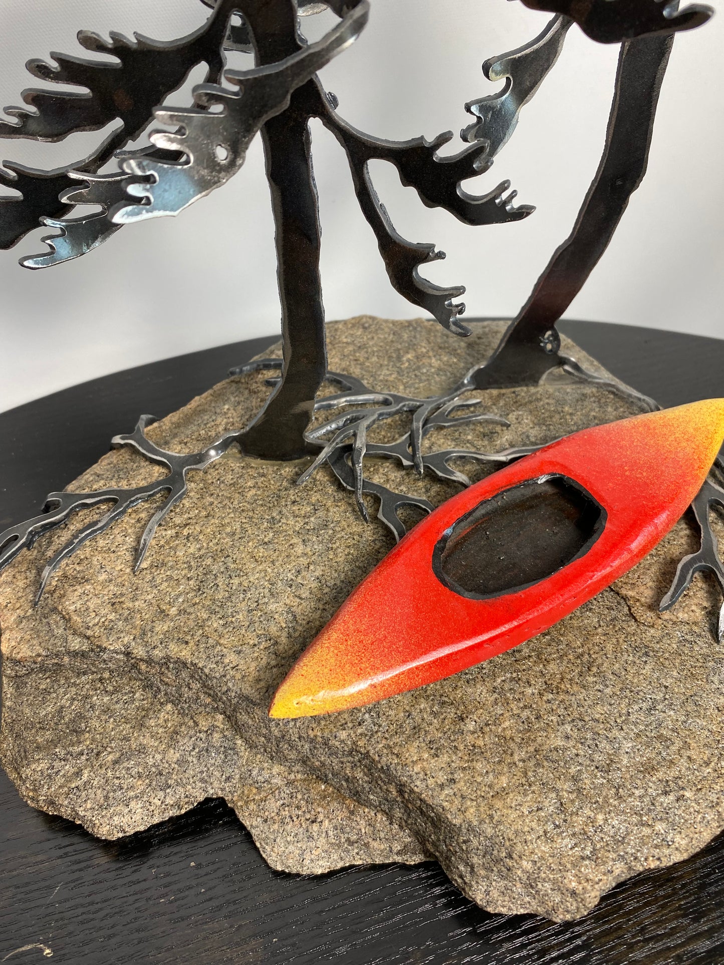 Metal windswept tree with kayak on granite