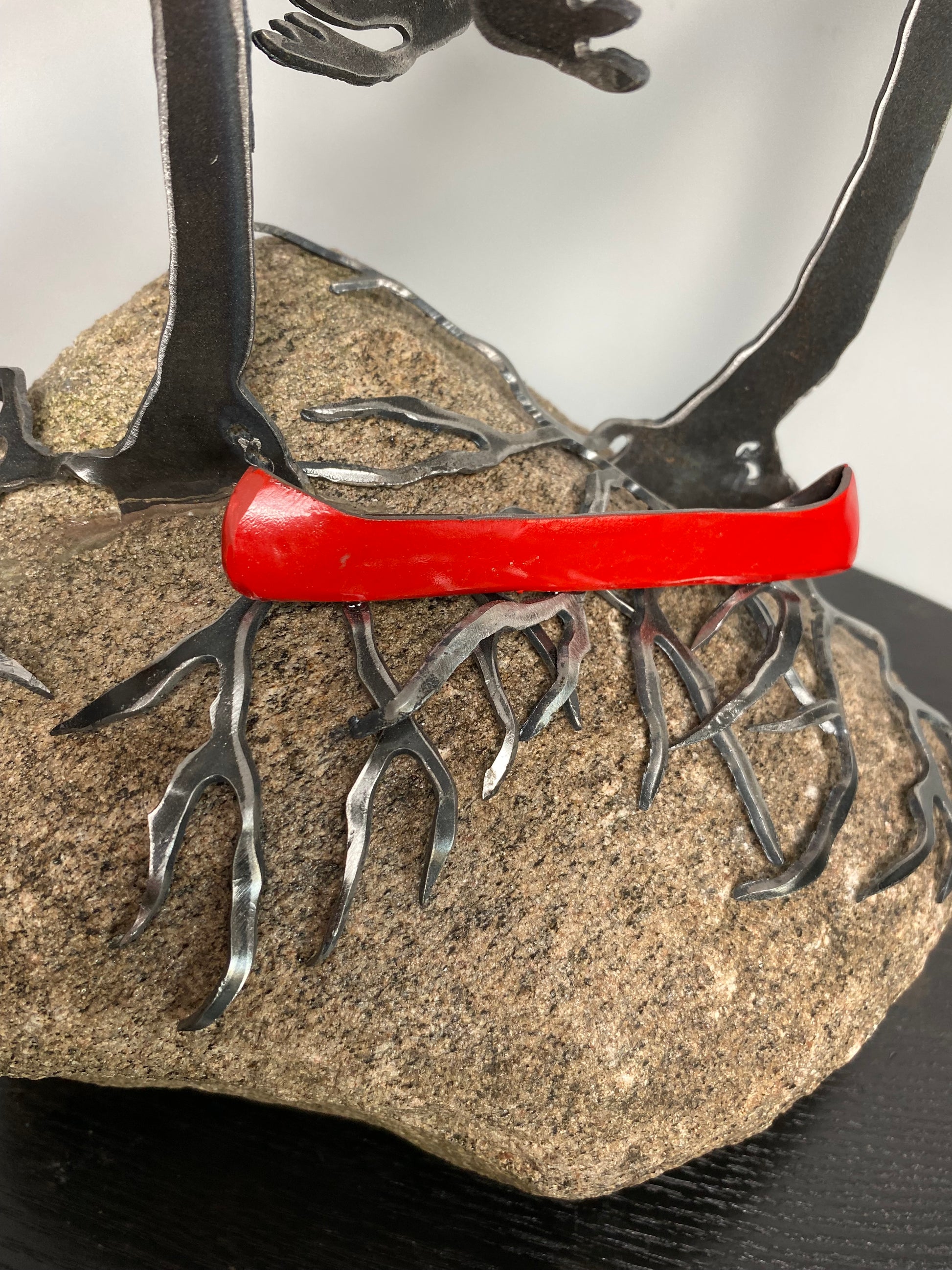 Metal windswept trees with canoe on granite