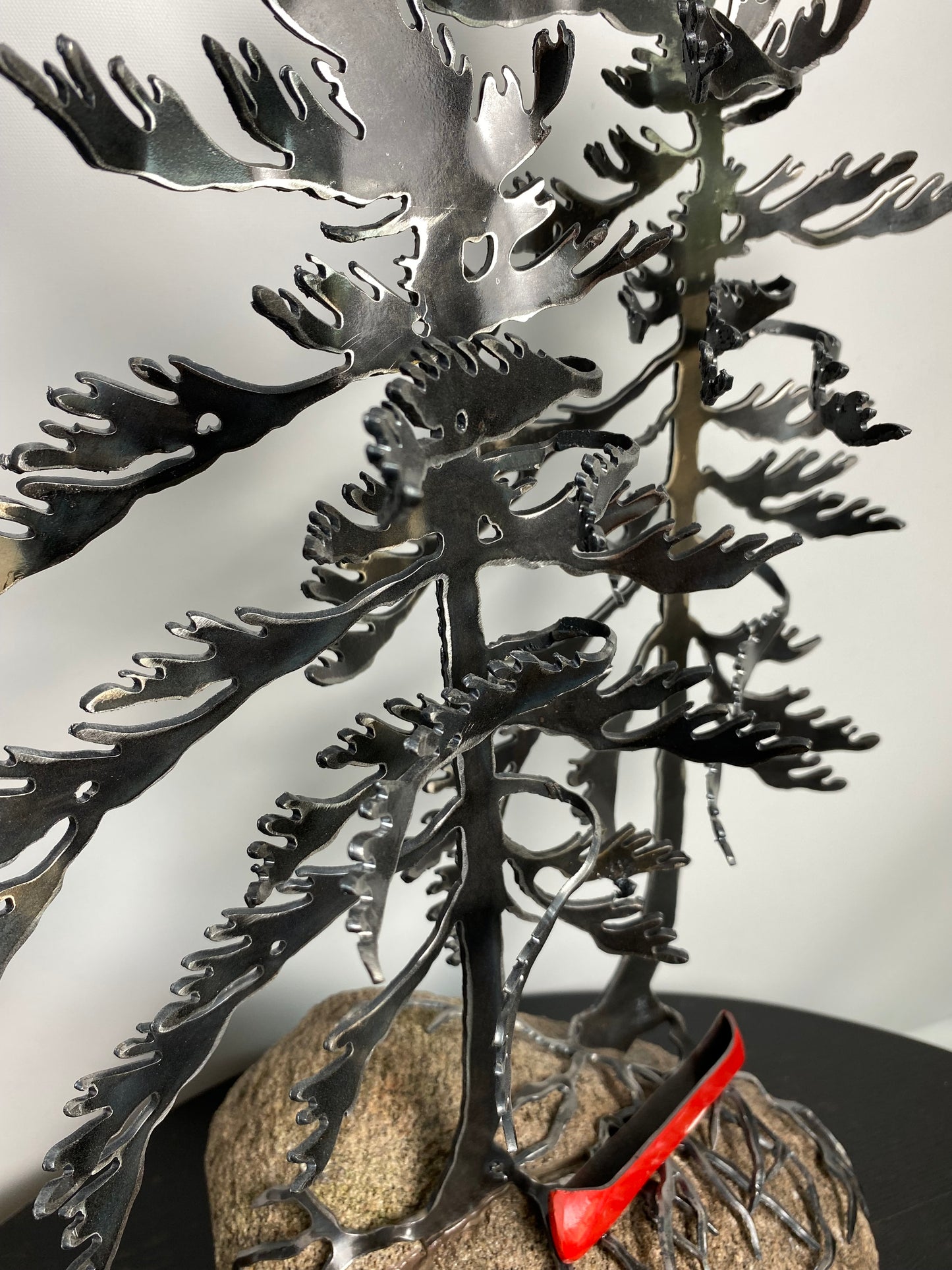 Metal windswept trees with canoe on granite