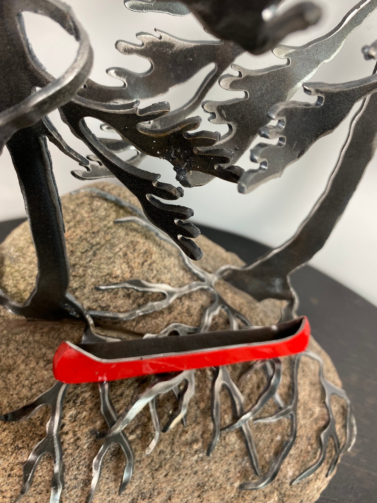 Metal windswept trees with canoe on granite