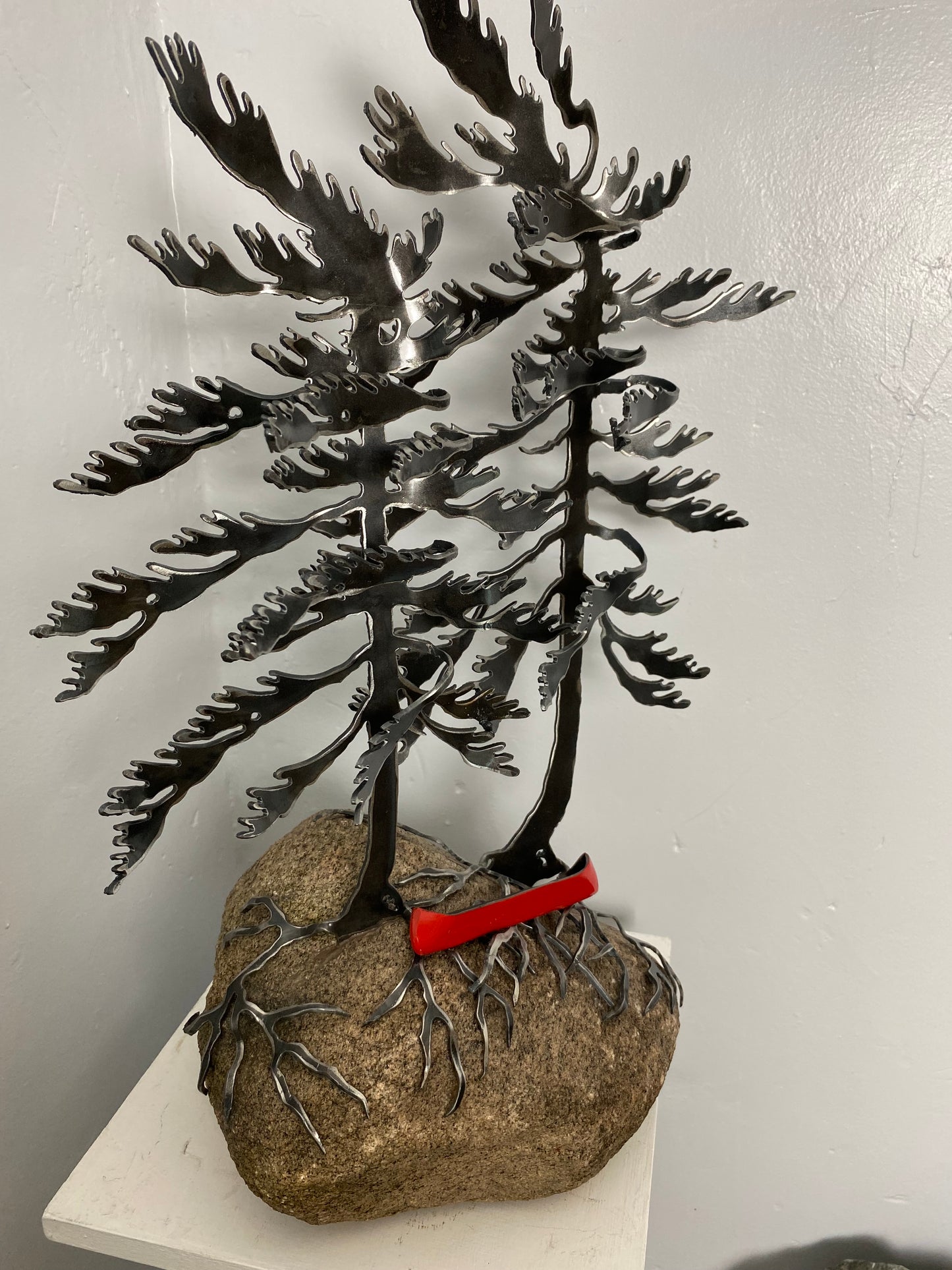 Metal windswept trees with canoe on granite