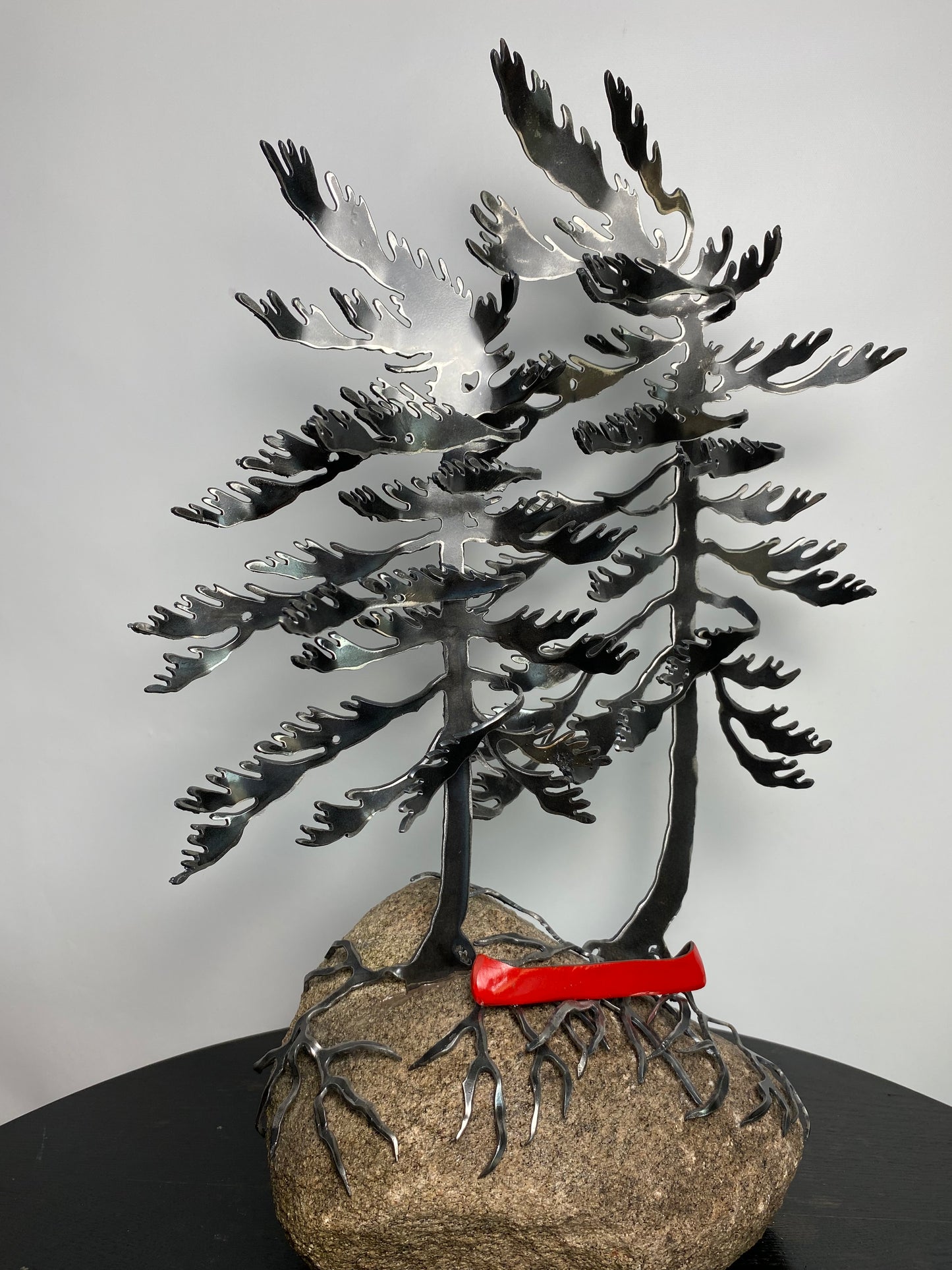 Metal windswept trees with canoe on granite
