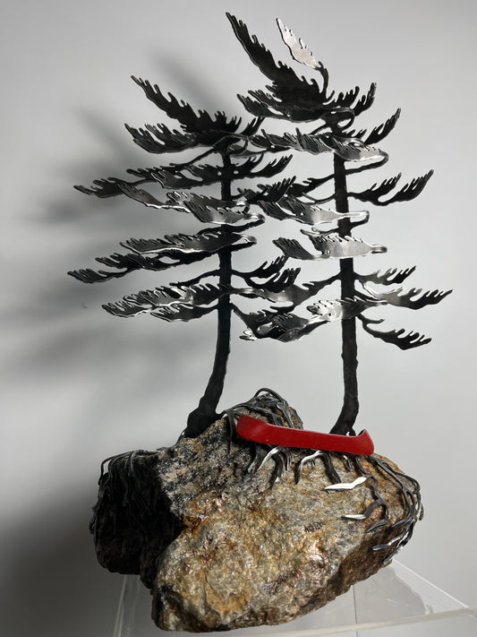 Metal windswept tree with canoe on granite