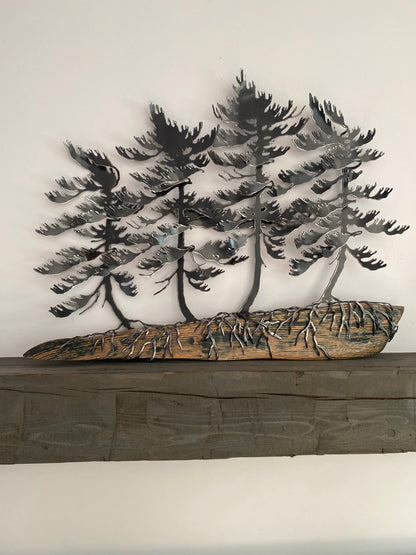 Metallic black pine tree wall art mounted above a rustic dark wood mantel against a plain off-white wall.