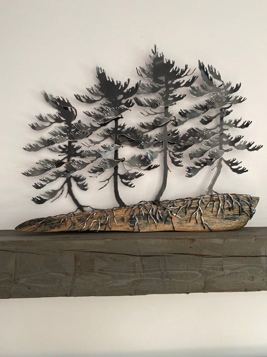Metallic black pine tree wall art mounted above a rustic dark wood mantel against a plain off-white wall.