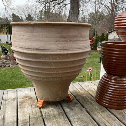 Large beige pot on a wooden deck with a grassy area and trees in the background