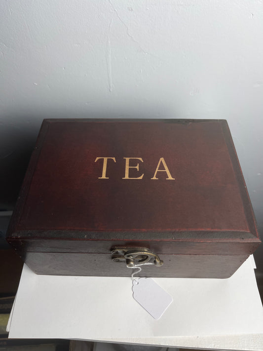 Wooden tea box with 'TEA' engraved on it against a plain background