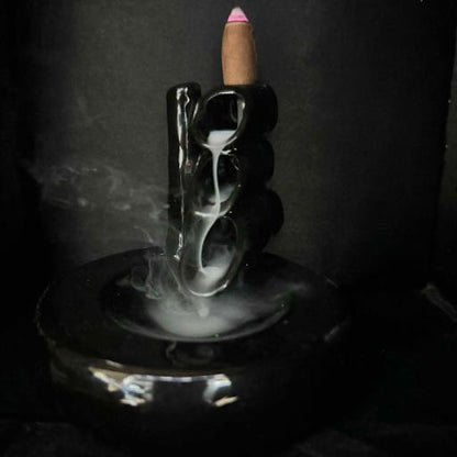 Incense stick with smoke in a black holder on a dark background