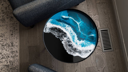 Overhead view of a round blue resin tabletop with white ocean-wave patterns and a black border.