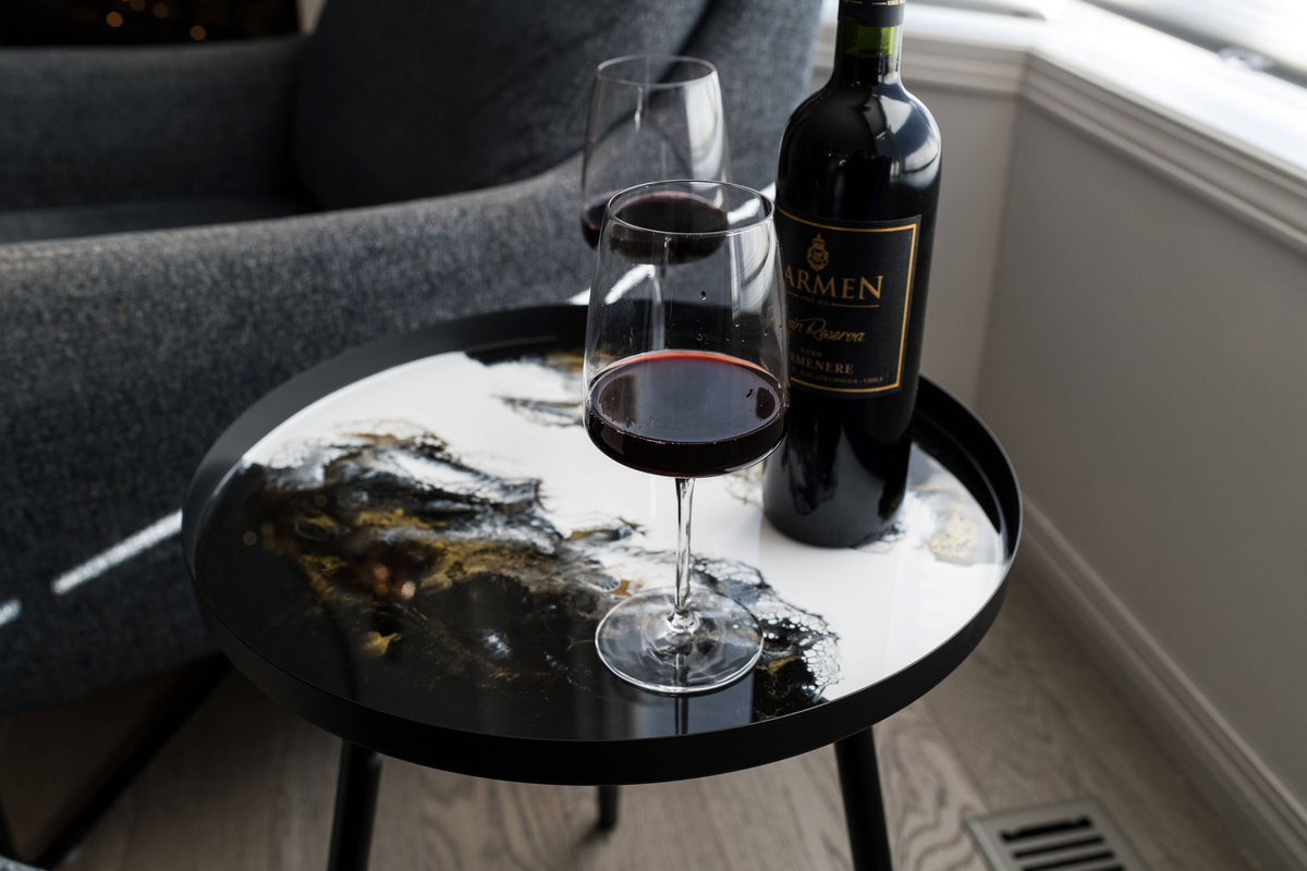 Close-up of black, white and gold resin tabletop patterns with a red wine bottle and glasses.