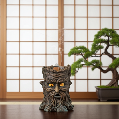 Tree-like incense burner with glowing eyes on a wooden surface with a bonsai tree in the background.