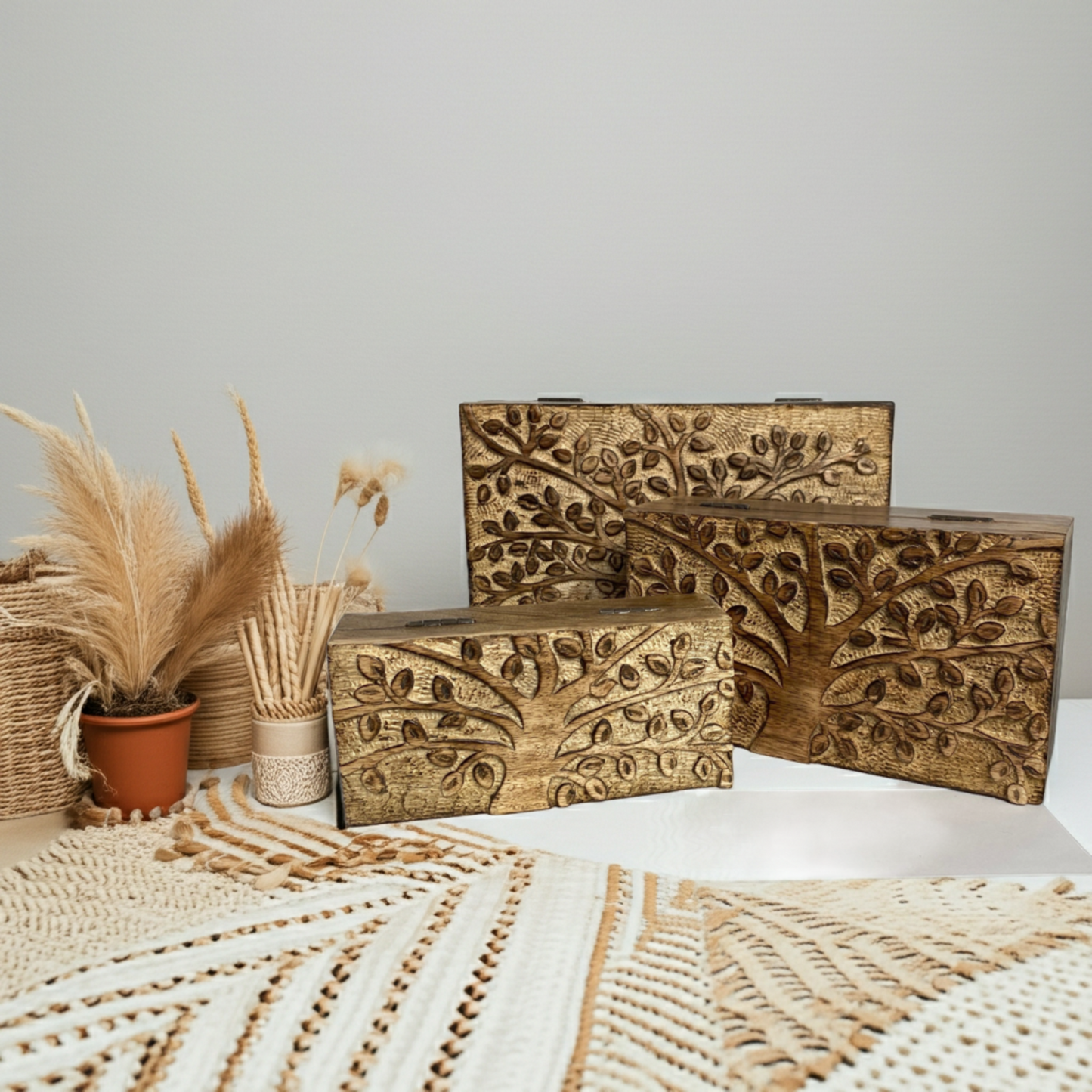 Set of three wooden boxes with tree carvings on a neutral background